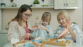 Three women baking and decorating cupcakes in a kitchen by Vitaly Gariev courtesy of Unsplash.