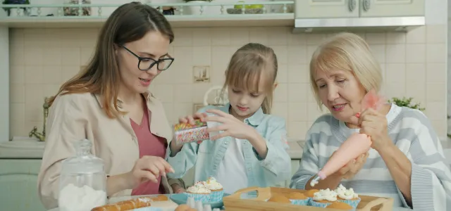Three women baking and decorating cupcakes in a kitchen by Vitaly Gariev courtesy of Unsplash.